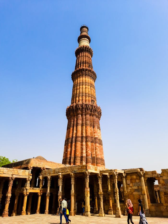 Historic Qutub Minar in Delhi with clear blue sky and ancient architecture.